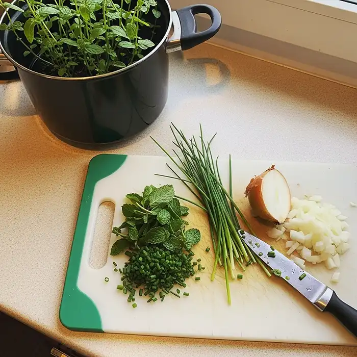 Best Indoor Herbs to Grow on a Windowsill 2 Freshly harvested indoor windowsill herbs on kitchen counter next to pot