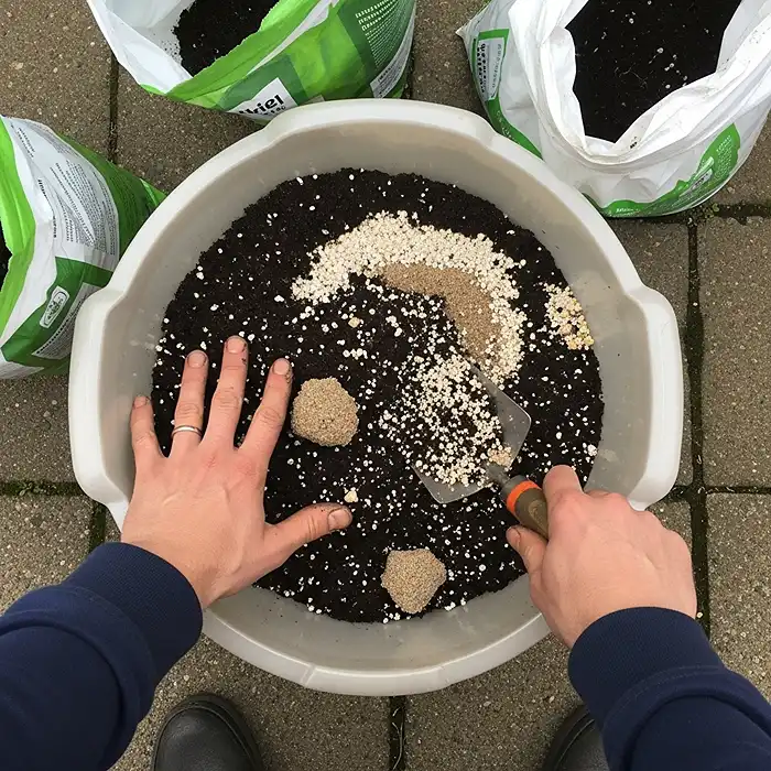 Mixing homemade potting soil with perlite and compost for herb containers