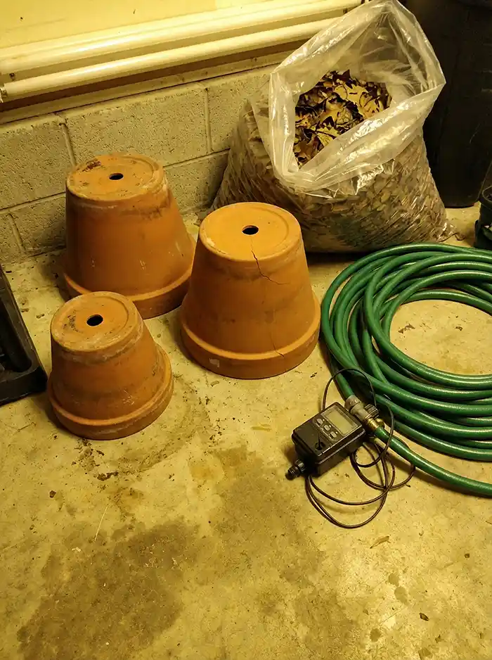Terra-cotta pots stored upside down and drip irrigation drained for winterizing raised beds