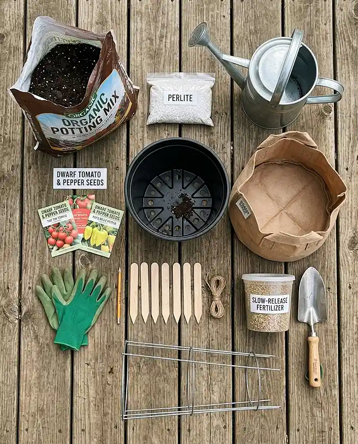 Container gardening supplies including pots, potting mix, perlite, fertilizer, and a tomato cage laid out for planting.