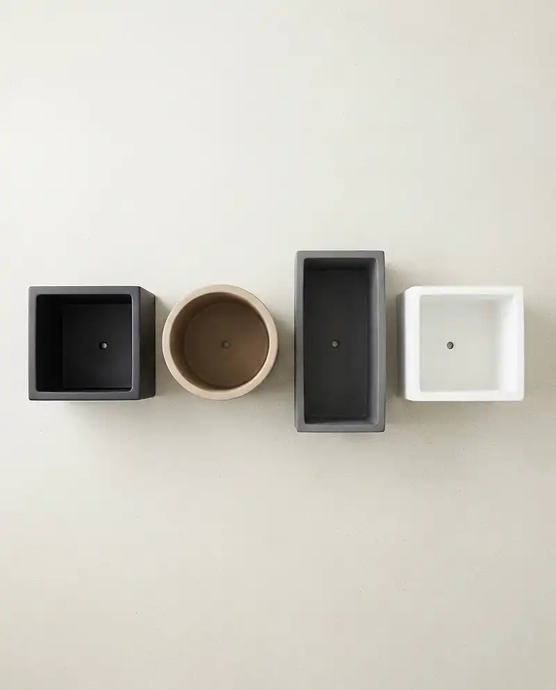 Neutral planters in matte black, beige, charcoal, and white for a minimalist balcony palette