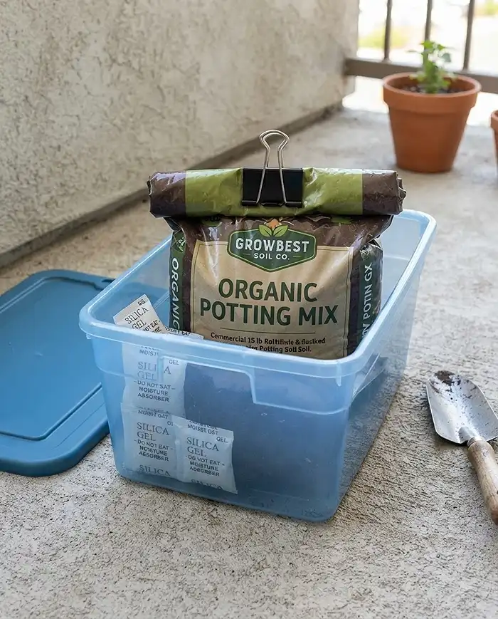Hidden Balcony Garden Storage That Blends With Planters 5 Soil bag sealed inside a watertight liner bin with silica packets to prevent mold in stored soil.