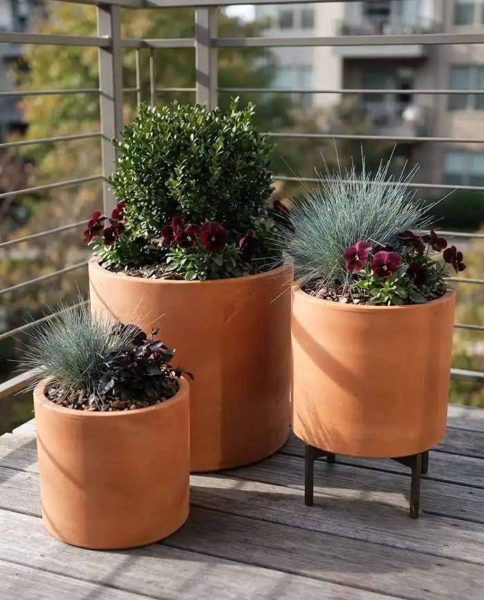 Fall Terracotta Balcony Ideas for a Modern Cozy Look 3 A grouped trio of clean-lined terracotta cylinders with structural plants, a core modern fall terracotta balcony idea