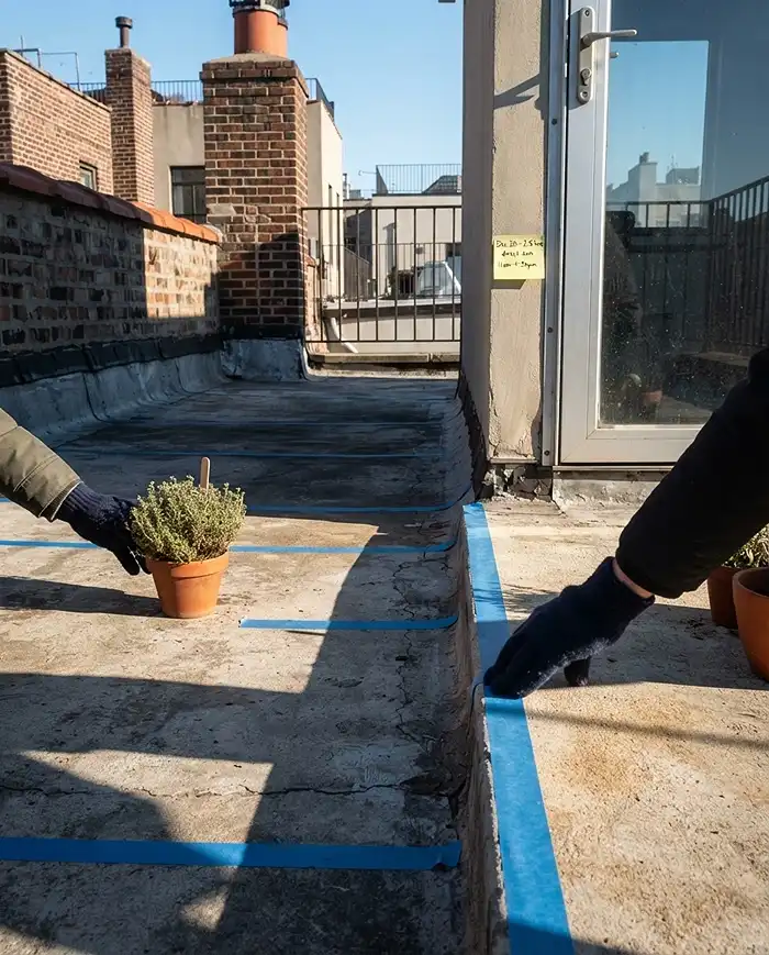 Winter Balcony Garden Lighting for Short Days 2 Taping shadow edges on a balcony floor under low winter sun and sliding a pot into light, assessing winter sun exposure.